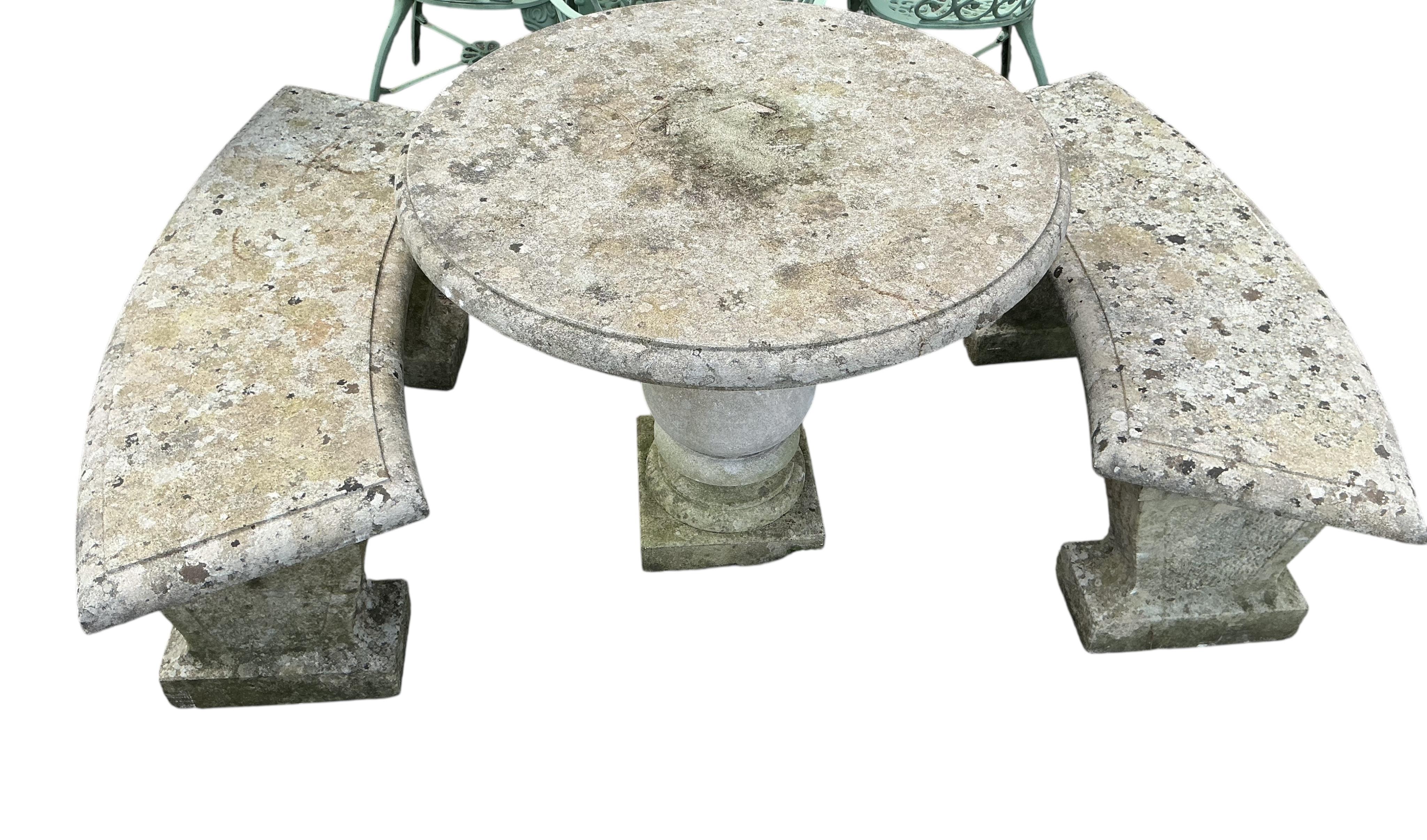 A circular reconstituted stone garden table, diameter 74cm, height 90cm, and two curved benches